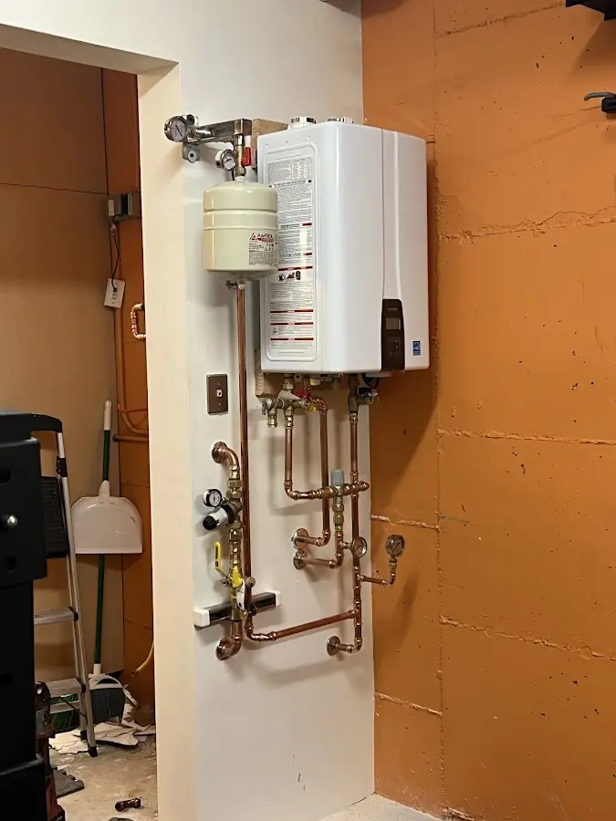 Plumbing technician inspecting water heater connections in Redford